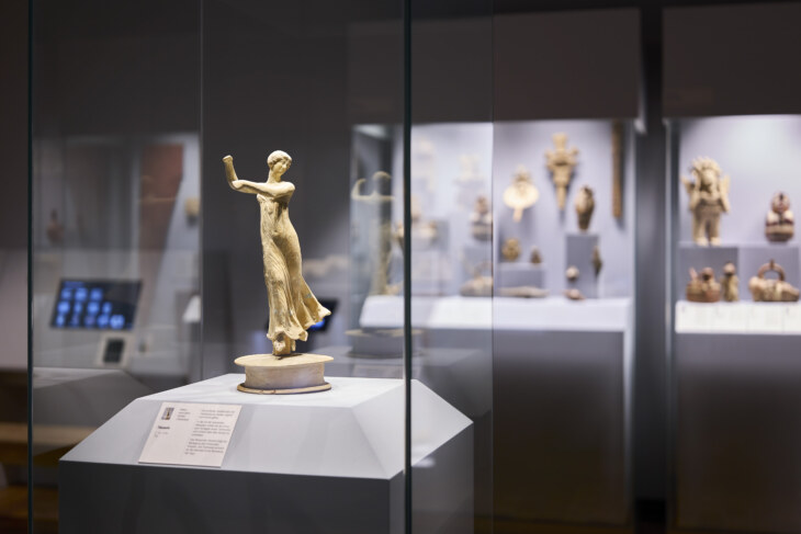 Figur einer Tänzerin aus Ton aus dem 2. Jh. v. Chr. aus Italien in der archäologischen Sammlung Ebnöther. Sie trägt ein Gewand und hat die Arme noch oben geschwungen.