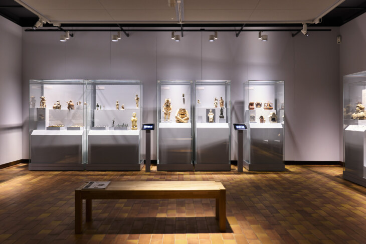 Drei Vitrinengruppen mit Objekten zu den Themen Gottheiten und Ritualstätten in der archäologischen Sammlung Ebnöther. Im Vordergrund steht eine Sitzbank.