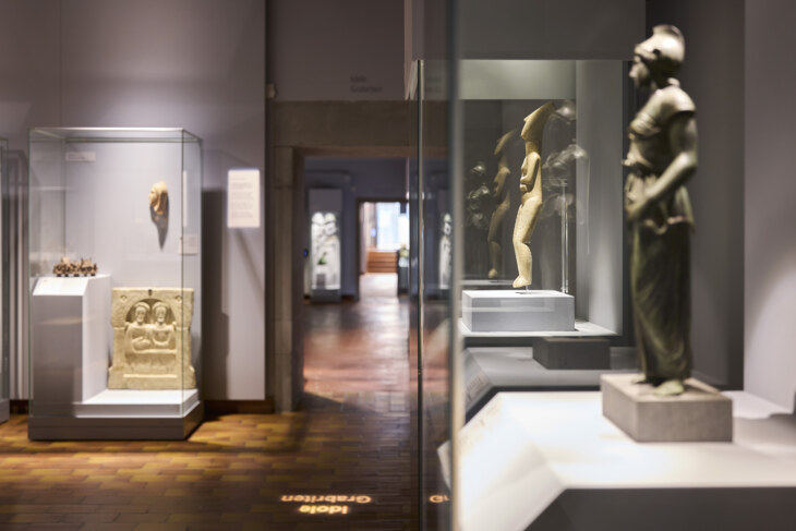 Blick in den Themenbereich Idole in der archäologischen Sammlung Ebnöther. Zwei Figuren sind in einer Vitrine zu sehen, weiter sieht man in den nächsten Raum hinein.