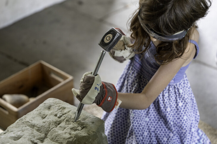 Mädchen bearbeitet einen Stein mit Hammer und Meissel am Erlebnisnachmittag für Klein und Gross