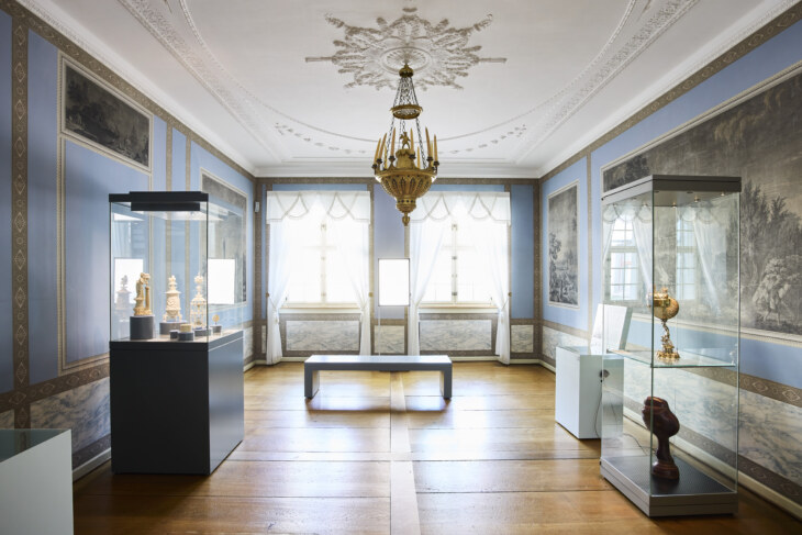 Blick in ein Historisches Zimmer mit Empire-Tapete und Elfenbein-Objekten.
