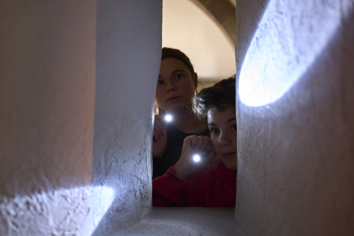 Zwei Kinder leuchten mit ihren Taschenlampen im dunklen Museum zu Allerheiligen.