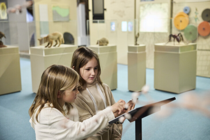 Zwei Mädchen stehen vor einer Texttafel in der naturkundlichen Abteilung des Museums.