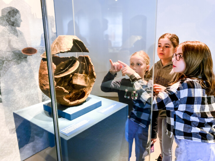Kinder erkunden eine Art Urne aus der Bronzezeit im Museum zu Allerheiligen